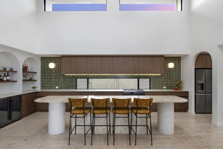 Modern kitchen with island, stools, and tiled backsplash.