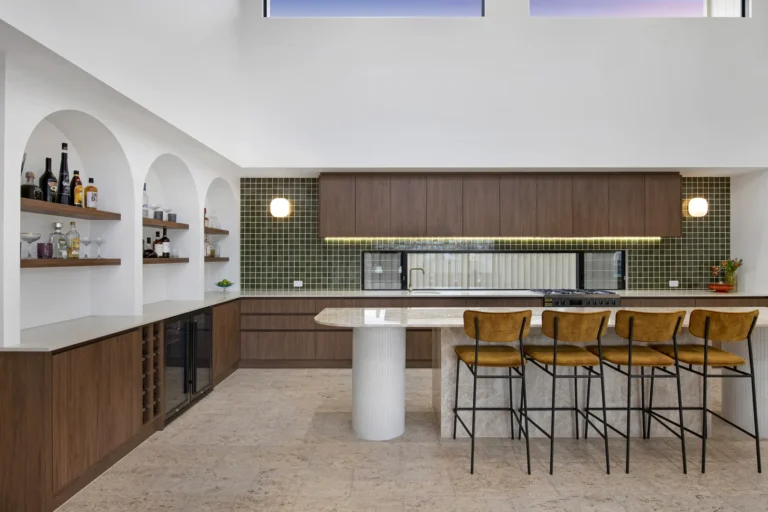Modern kitchen with bar, oven, and green backsplash.