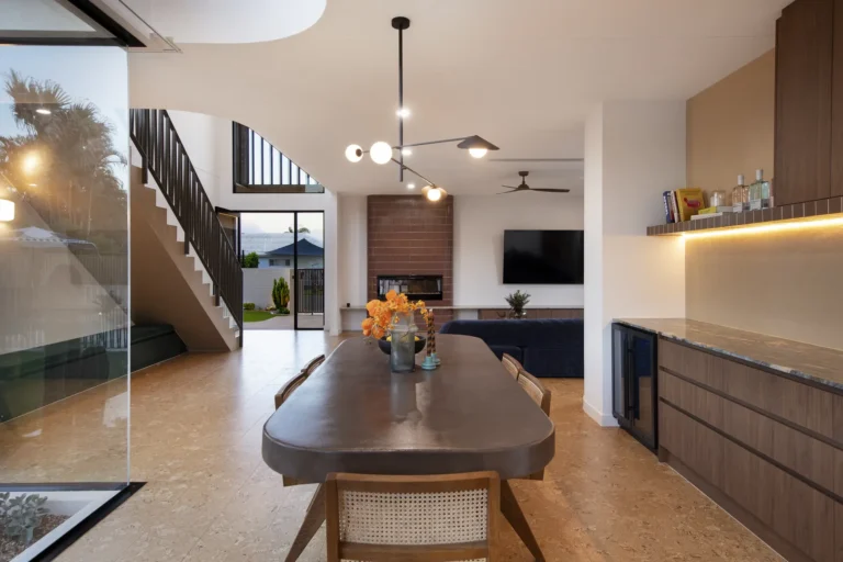 Modern dining area with open staircase and fireplace.