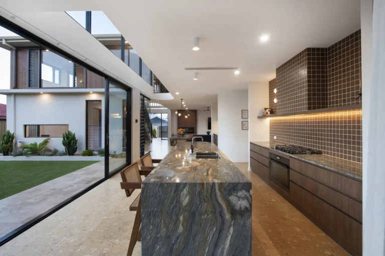 Modern open kitchen with marble island and outdoor view.