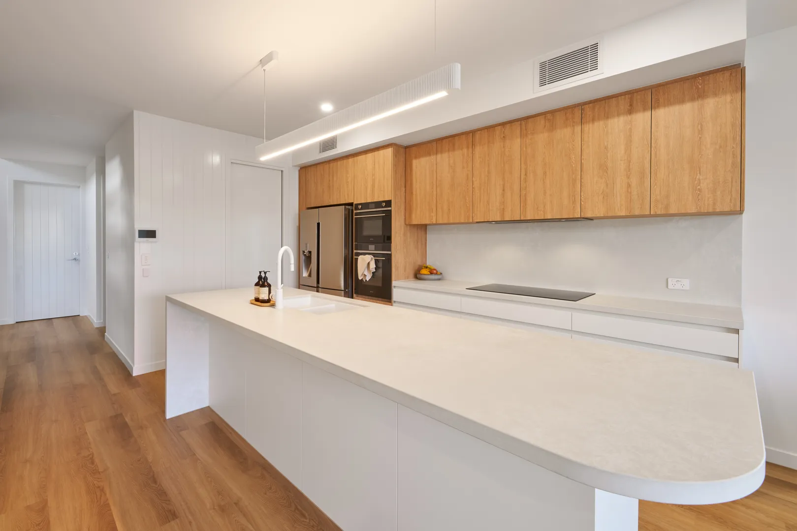 Modern kitchen with wooden cabinets and white counters.