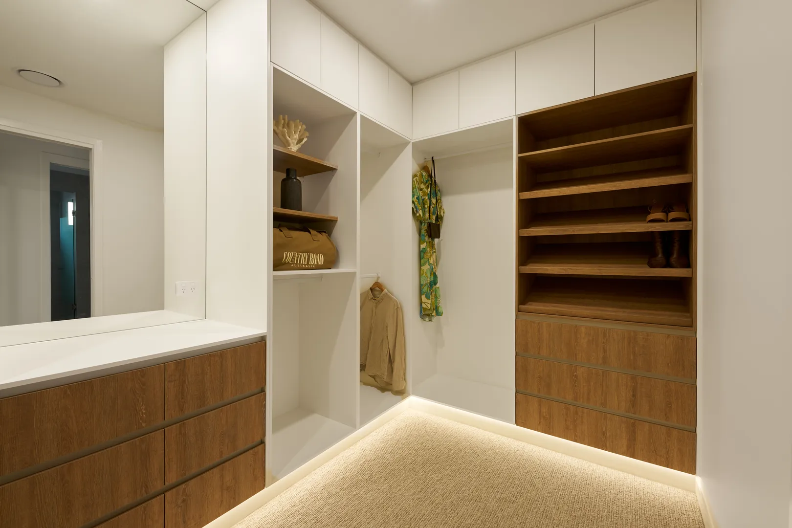 Modern walk-in closet with wooden shelves and drawers.