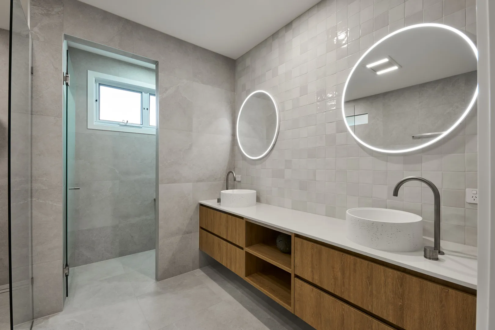 Modern bathroom with floating vanity and round mirrors.